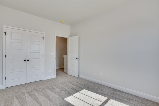 unfurnished bedroom with light carpet and a closet