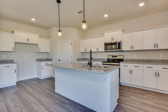 kitchen featuring hanging light fixtures, an island with sink, white cabinets, and appliances with stainless steel finishes