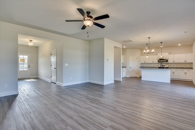 unfurnished living room with ceiling fan with notable chandelier and wood-type flooring