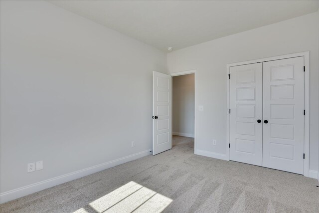 unfurnished bedroom featuring light carpet and a closet