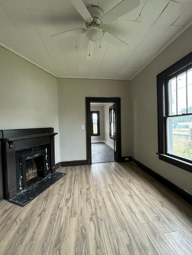 unfurnished living room featuring ceiling fan, light wood-type flooring, ornamental molding, and a tiled fireplace