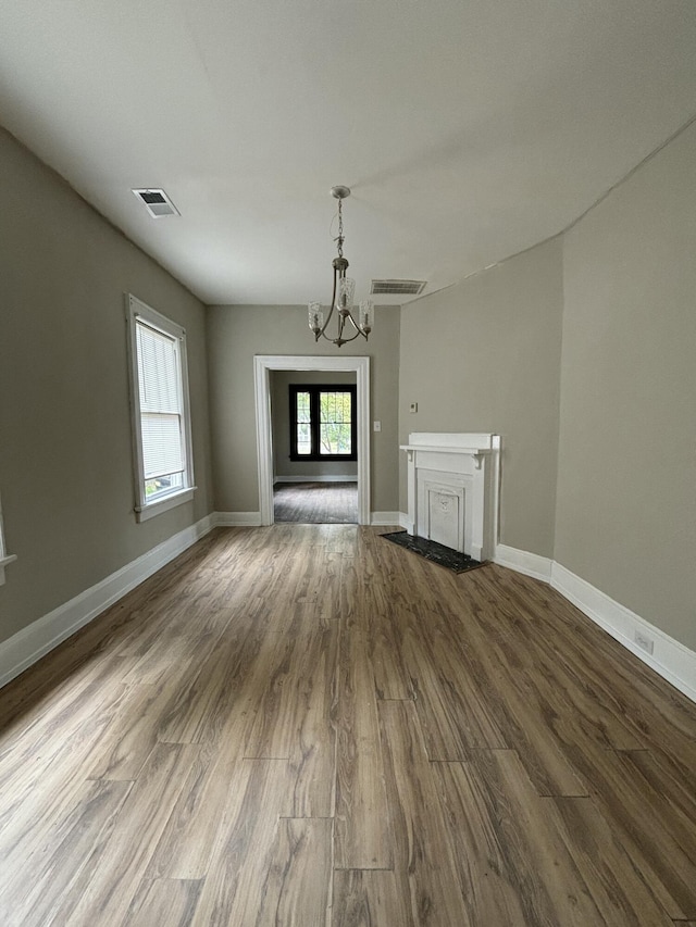 unfurnished living room featuring a chandelier and wood-type flooring