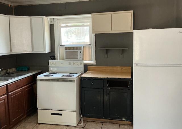 kitchen with sink, white appliances, cooling unit, dark brown cabinets, and light tile patterned flooring