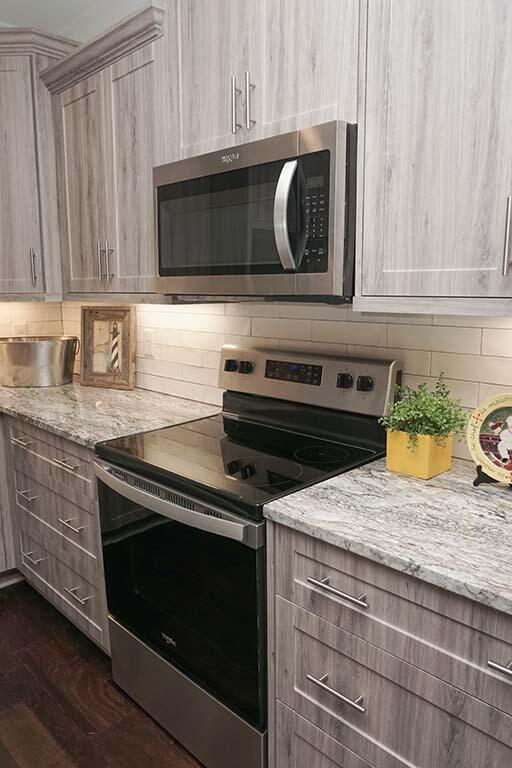 kitchen with dark hardwood / wood-style flooring, backsplash, light stone counters, stainless steel appliances, and light brown cabinets