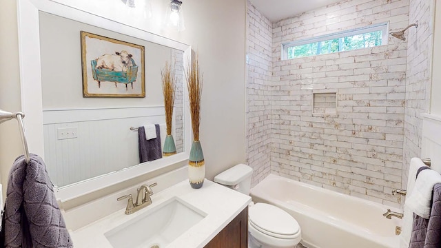 full bathroom featuring vanity, tiled shower / bath combo, and toilet