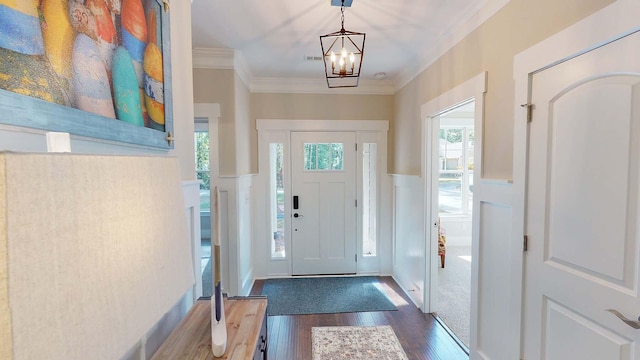 entrance foyer featuring crown molding, dark wood-type flooring, and a notable chandelier