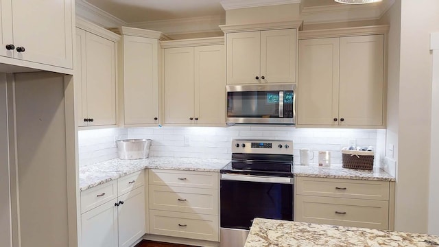 kitchen featuring backsplash, light stone counters, stainless steel appliances, and cream cabinetry