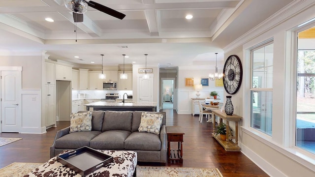 living room with dark wood-type flooring, coffered ceiling, beamed ceiling, ceiling fan with notable chandelier, and ornamental molding