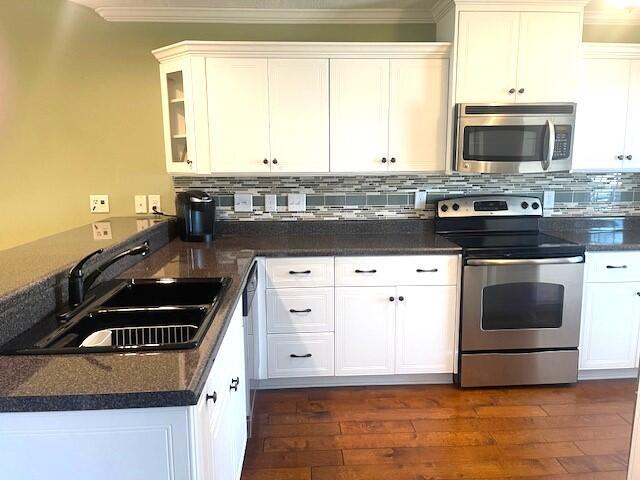 kitchen with appliances with stainless steel finishes, sink, dark hardwood / wood-style flooring, and white cabinets