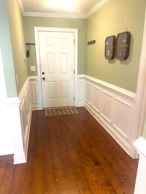 doorway featuring ornamental molding and dark wood-type flooring