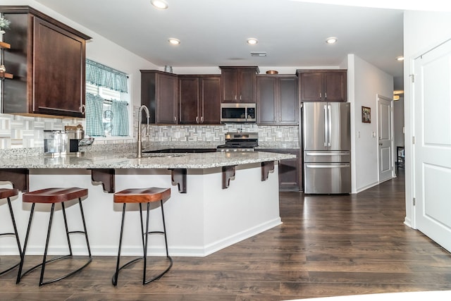 kitchen featuring stainless steel appliances, dark hardwood / wood-style flooring, sink, and light stone counters