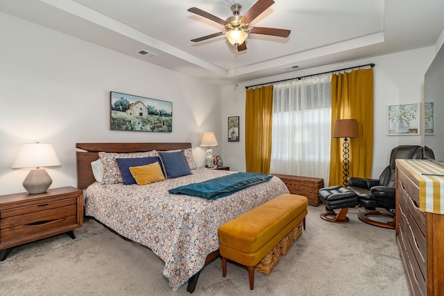 carpeted bedroom featuring ceiling fan and a tray ceiling