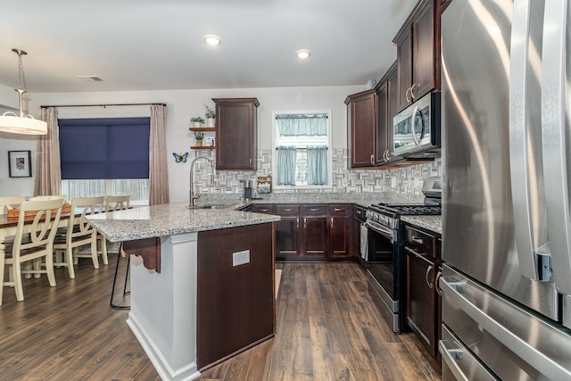 kitchen featuring pendant lighting, a breakfast bar area, dark wood-type flooring, stainless steel appliances, and decorative backsplash