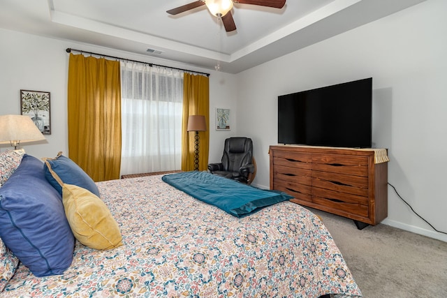 carpeted bedroom featuring a raised ceiling and ceiling fan