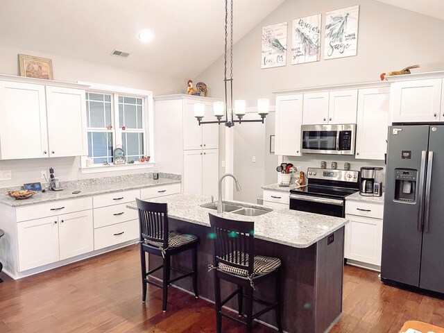 kitchen featuring white cabinetry, hanging light fixtures, stainless steel appliances, and a center island with sink