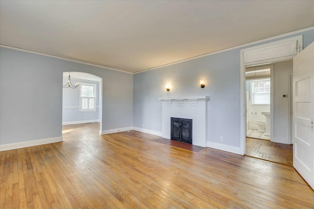 unfurnished living room with crown molding, a healthy amount of sunlight, a fireplace, and light hardwood / wood-style floors