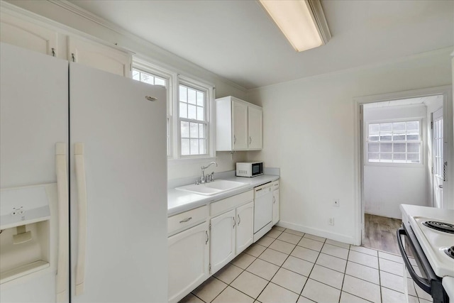 kitchen with sink, light tile patterned floors, white cabinets, and white appliances