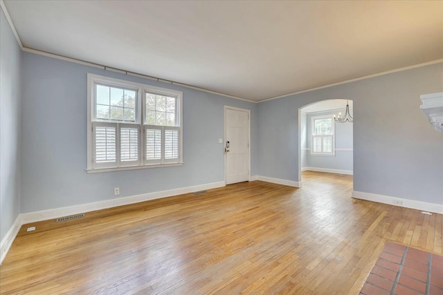 spare room featuring an inviting chandelier, light hardwood / wood-style flooring, and ornamental molding