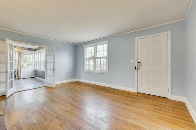 entryway featuring ornamental molding, an inviting chandelier, light hardwood / wood-style floors, and french doors