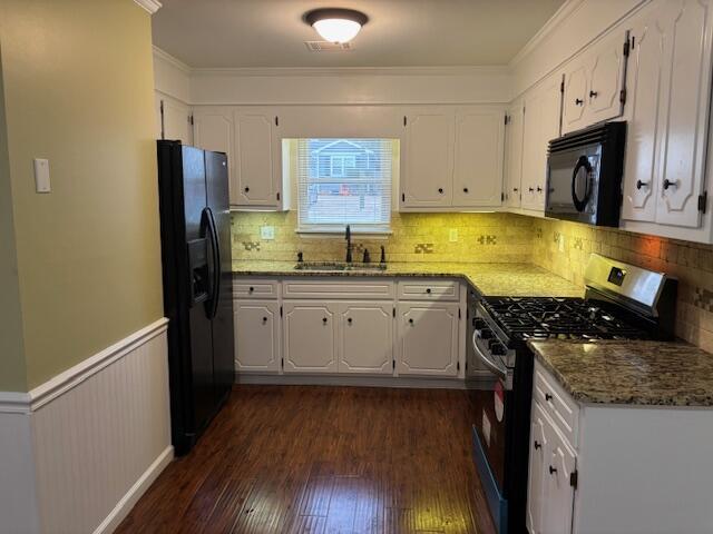 kitchen with white cabinetry, sink, dark stone countertops, black appliances, and dark wood-type flooring