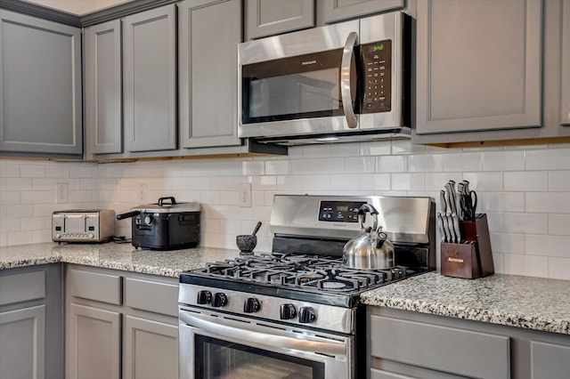 kitchen featuring appliances with stainless steel finishes, gray cabinets, and light stone countertops