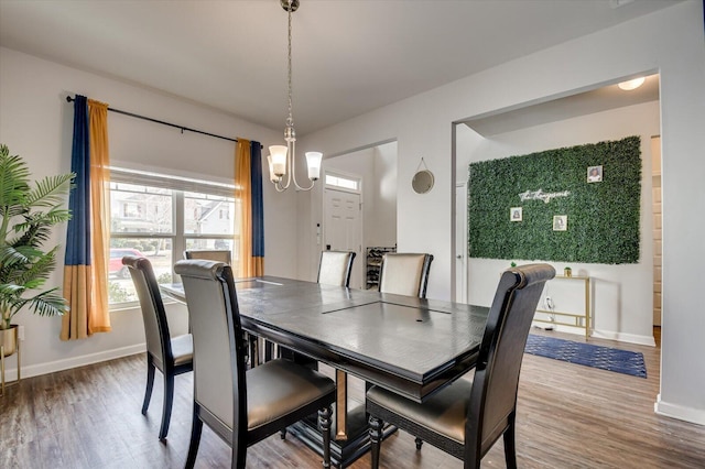 dining space with baseboards, an inviting chandelier, and wood finished floors