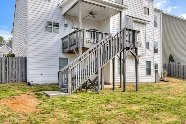 rear view of house with a deck, fence, a lawn, and stairs