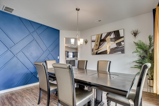 dining space featuring visible vents, a notable chandelier, baseboards, and wood finished floors