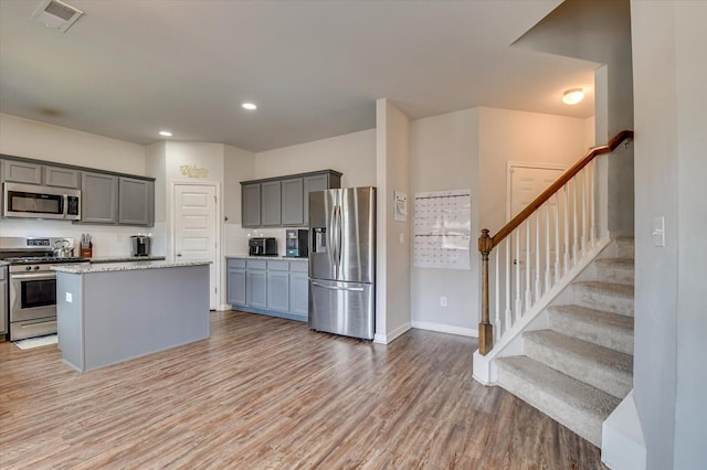 kitchen featuring a center island, light wood finished floors, visible vents, gray cabinetry, and appliances with stainless steel finishes