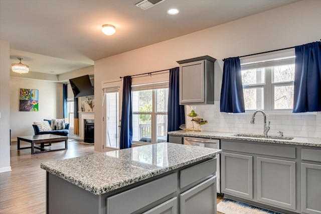 kitchen featuring tasteful backsplash, a kitchen island, gray cabinets, and a sink