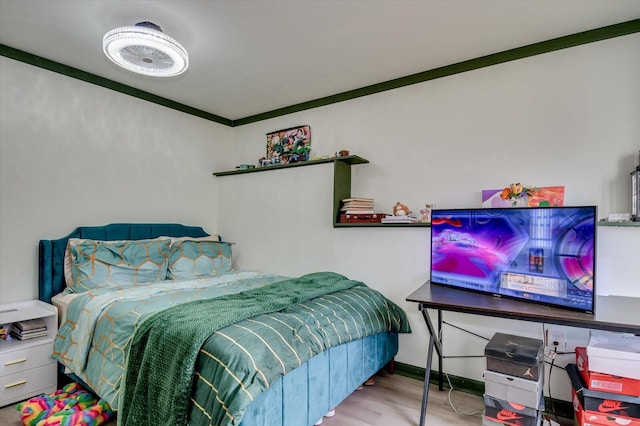 bedroom featuring ornamental molding, light wood-style flooring, and baseboards