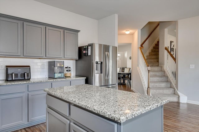 kitchen featuring stainless steel fridge, decorative backsplash, a kitchen island, dark wood-style flooring, and gray cabinetry