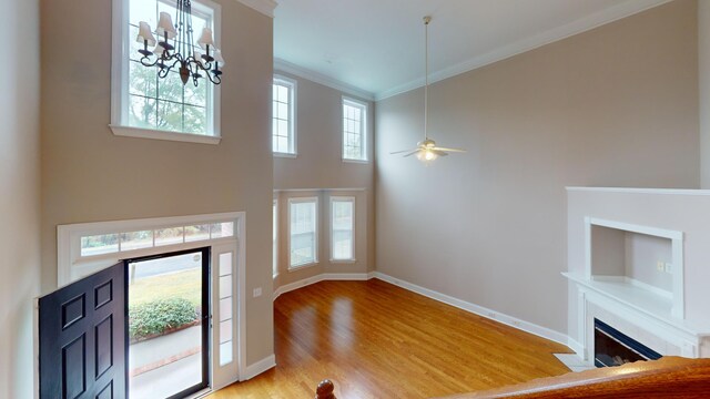 135 Coach Ln, Augusta, GA 30907 - foyer featuring a fireplace with flush hearth, wood finished floors, crown molding, baseboards, and ceiling fan with notable chandelier