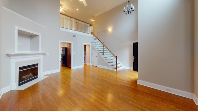 135 Coach Ln, Augusta, GA 30907 - unfurnished living room with ceiling fan with notable chandelier, wood finished floors, a high ceiling, stairs, and a tile fireplace