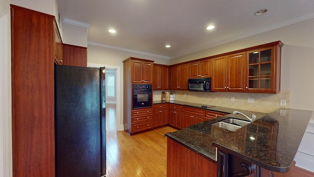 135 Coach Ln, Augusta, GA 30907 - kitchen with light wood finished floors, a sink, black appliances, a peninsula, and glass insert cabinets