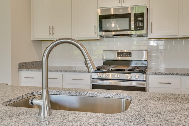909 Kay Pl, Grovetown, GA 30813 - kitchen with stainless steel appliances, light stone counters, white cabinets, and backsplash