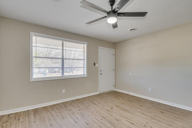 empty room featuring light wood finished floors, baseboards, a ceiling fan, and visible vents