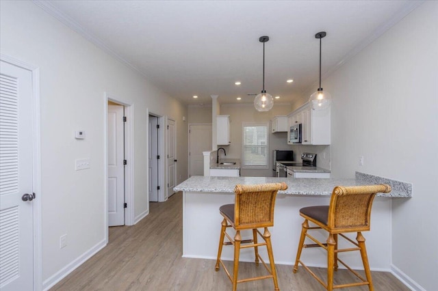 kitchen featuring sink, decorative light fixtures, kitchen peninsula, stainless steel appliances, and white cabinets