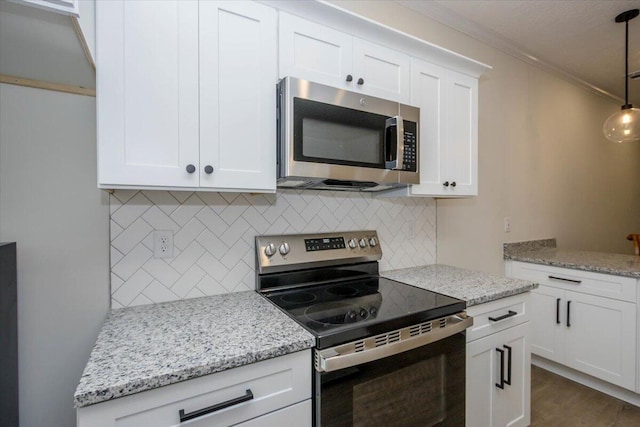 kitchen featuring white cabinetry, decorative light fixtures, ornamental molding, appliances with stainless steel finishes, and backsplash