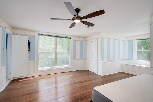 unfurnished bedroom featuring wallpapered walls, a ceiling fan, and hardwood / wood-style flooring