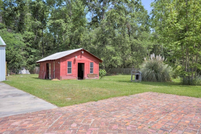 view of outdoor structure with fence and an outbuilding