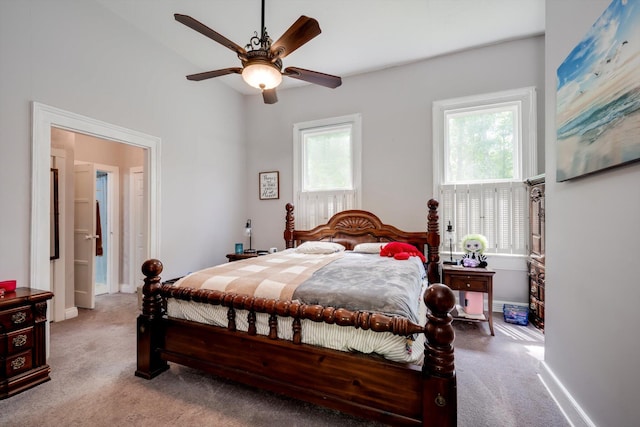 carpeted bedroom with ceiling fan, multiple windows, and baseboards