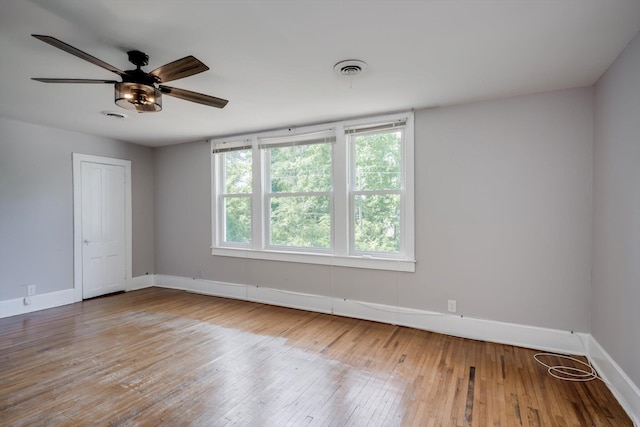spare room featuring a ceiling fan, baseboards, visible vents, and hardwood / wood-style flooring