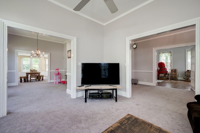 carpeted living room with crown molding, baseboards, vaulted ceiling, and ceiling fan with notable chandelier