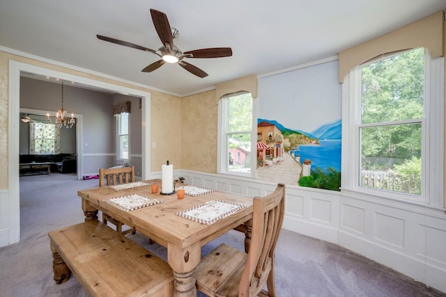 carpeted dining room with wainscoting, ceiling fan with notable chandelier, and a decorative wall