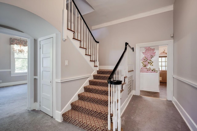 staircase featuring baseboards, a notable chandelier, ornamental molding, and carpet