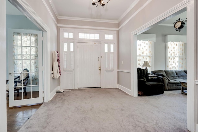carpeted foyer entrance with baseboards and ornamental molding