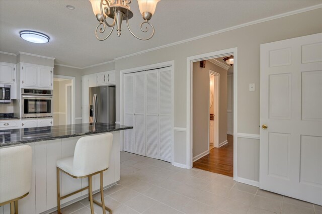 986 Campbellton Dr, North Augusta, SC 29841 - kitchen with stainless steel appliances, ornamental molding, a chandelier, white cabinetry, and dark stone countertops