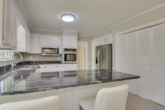 986 Campbellton Dr, North Augusta, SC 29841 - kitchen featuring appliances with stainless steel finishes, a peninsula, ornamental molding, white cabinetry, and dark stone countertops