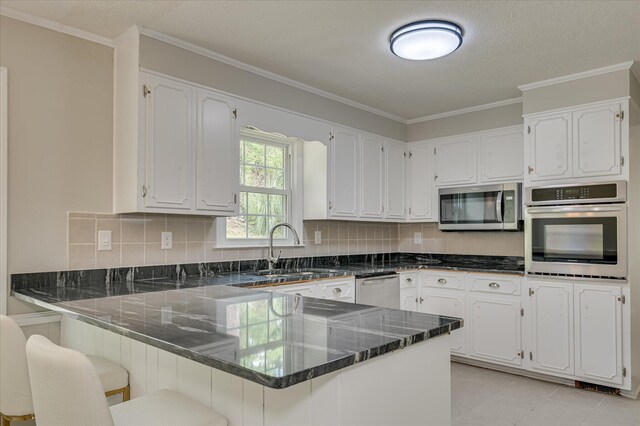 986 Campbellton Dr, North Augusta, SC 29841 - kitchen with appliances with stainless steel finishes, a peninsula, white cabinetry, dark stone countertops, and decorative backsplash
